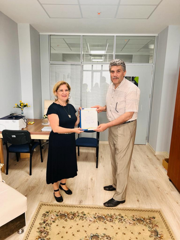 Prof. Dr. Figen Akça Personel Daire Başkanı Rıdvan Uslu'dan belgesini alırken